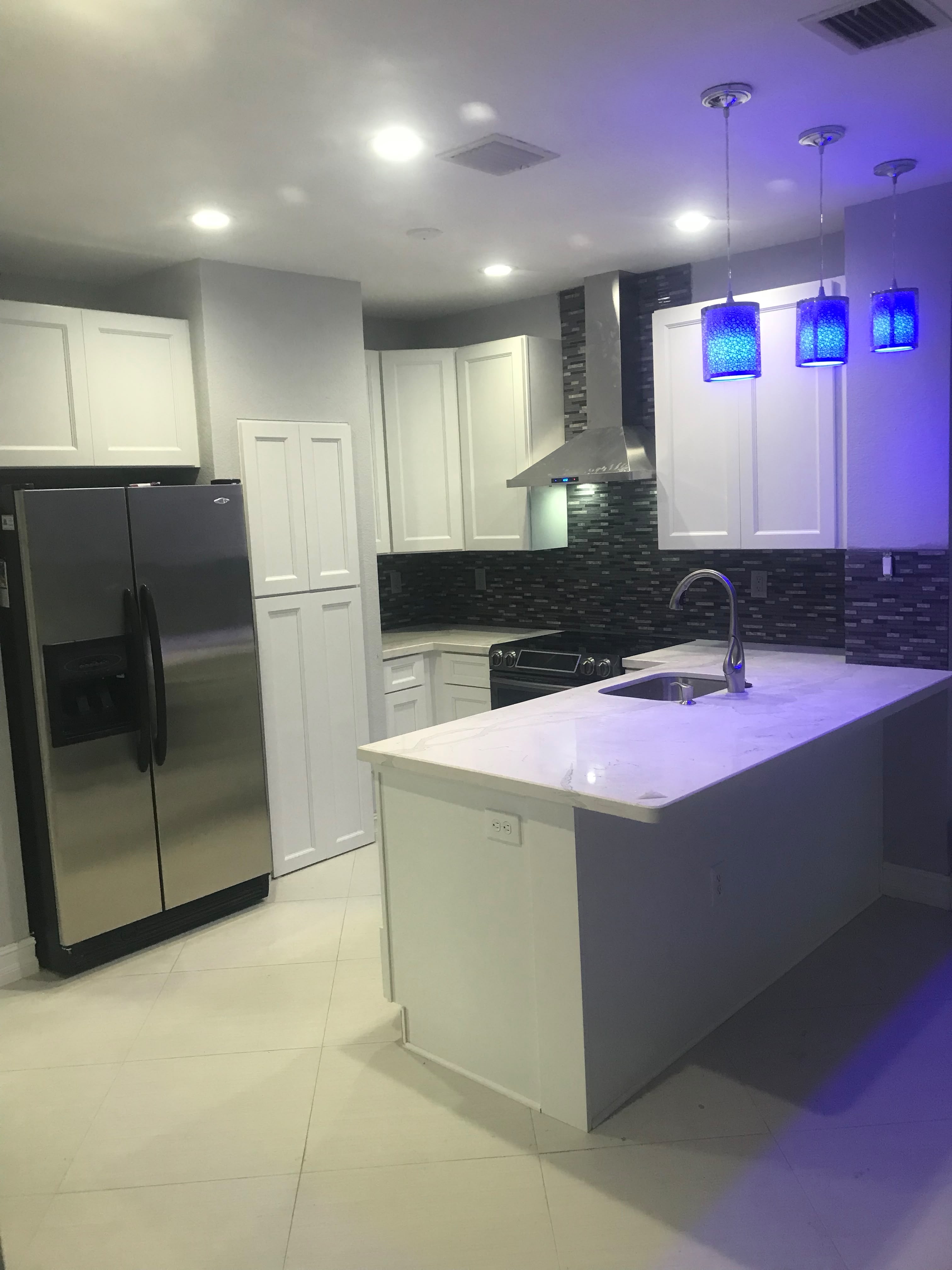 Contemporary kitchen with dark backsplash and blue pendants